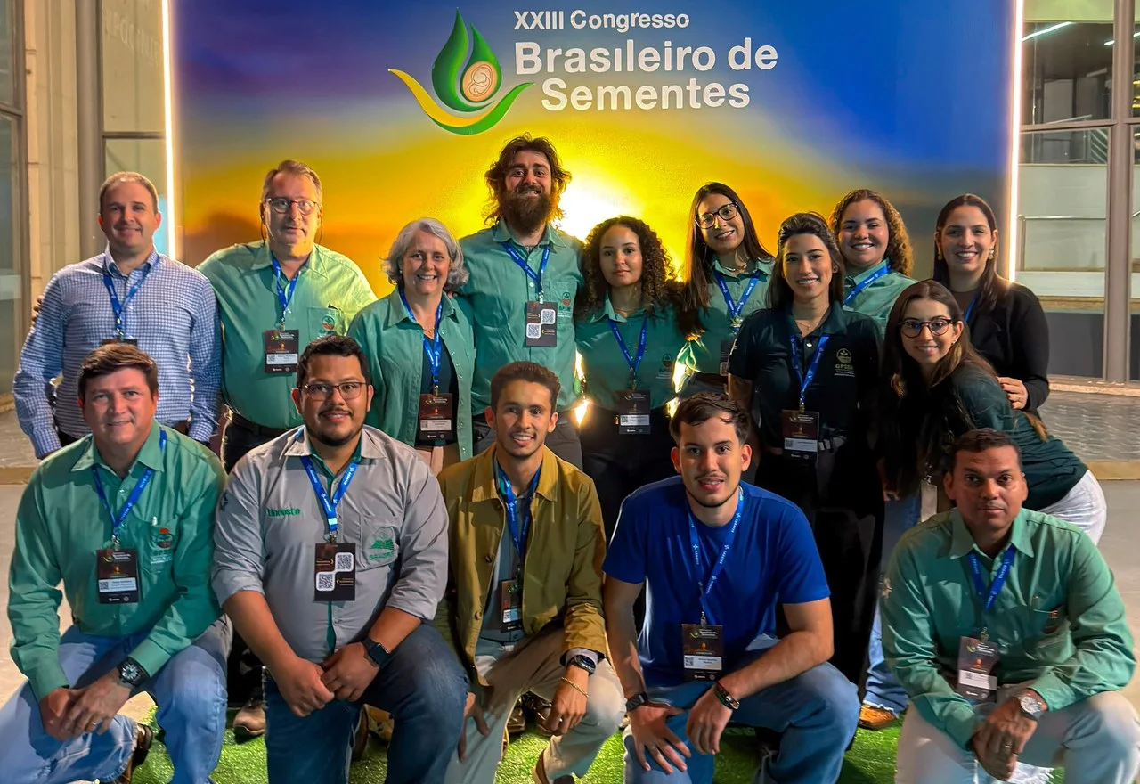 O grupo, de camisa verde, posa em duas fileiras diante do painel do XXIII Congresso Brasileiro de Sementes.